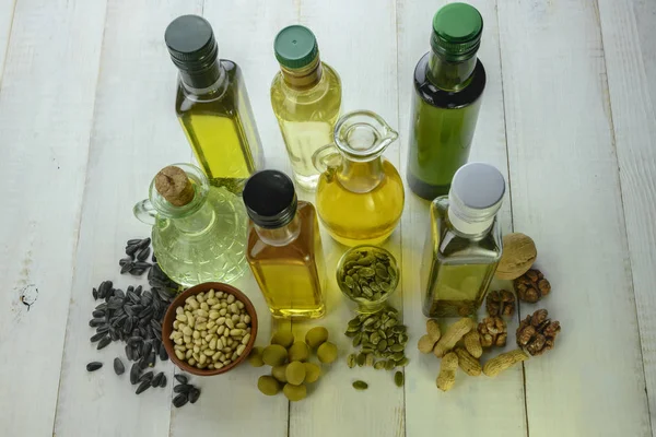 Várias garrafas de óleo diferente estão em uma mesa de madeira — Fotografia de Stock