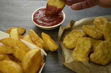 El külçeleri alır ve domates sosuna batırır.