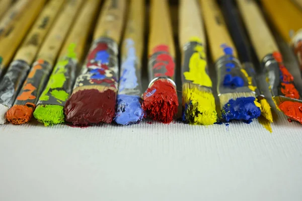 Brushes with different paints lie on canvas — Stock Photo, Image