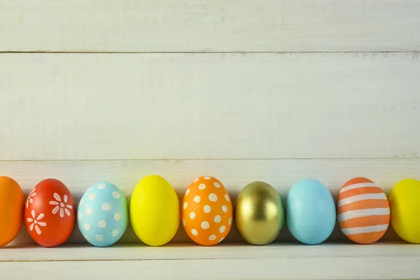 different colored eggs lie on a wooden background