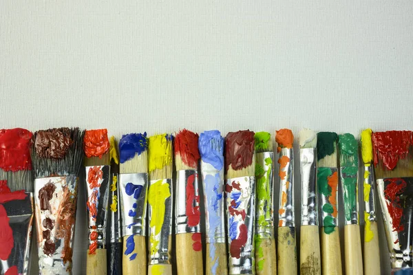 Brushes with different paints lie on canvas — Stock Photo, Image