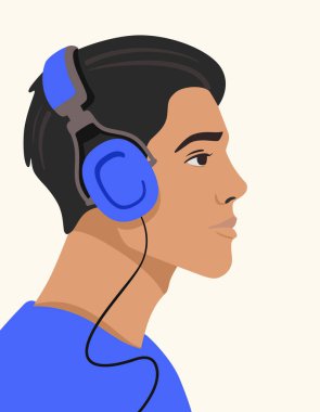 Genç adam kulaklıkla müzik dinliyor.