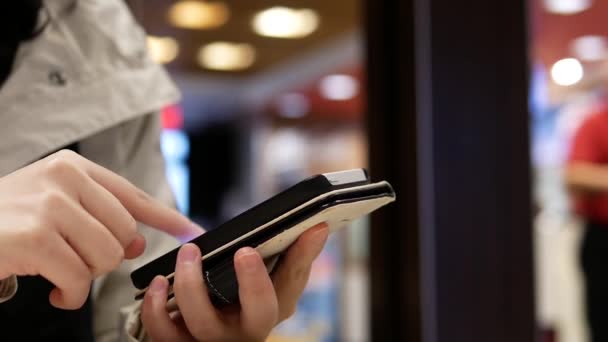 Mulher usando seu telefone celular no belo fundo de iluminação borrada dentro do restaurante Mcdonalds — Vídeo de Stock
