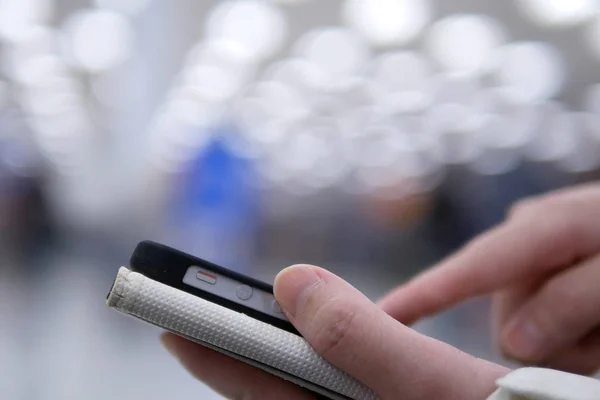 Vrouw met behulp van haar mobiele telefoon op de achtergrond mooie wazig verlichting — Stockfoto