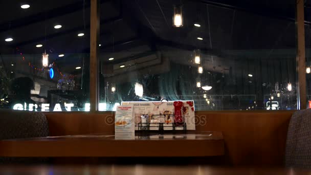 Motion of waitress serving water for customer with reflection on window inside Denny's restaurant — Stock Video