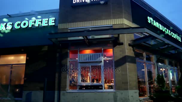 Ozione di persone che bevono caffè e chattano al negozio Starbucks durante la notte di pioggia — Video Stock