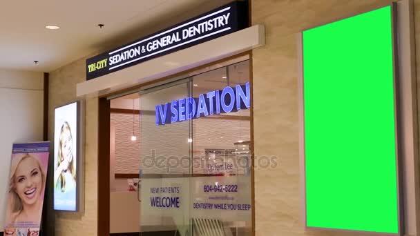 Grön skylt för annonsen på väggen bredvid tandvård store inne Coquitlam köpcentrum — Stockvideo
