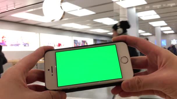 Frau hält ein leeres Smart-Gerät mit grünem Bildschirm für eigene Inhalte vor dem Apple Store — Stockvideo