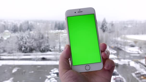 男人拥有空白智能手机和攻丝与雪自然背景的绿色屏幕上. — 图库视频影像
