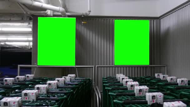 Рядок порожніх візків перед покупкою низькопродуктового супермаркету з двома зеленими дошками екрану — стокове відео