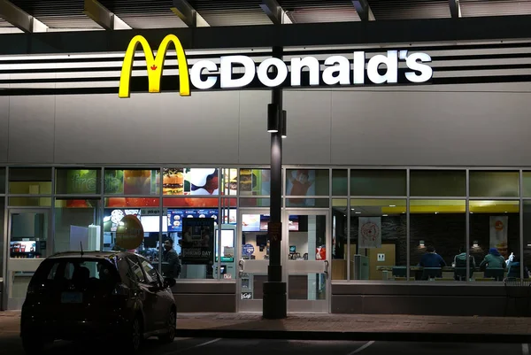 Foto notturna di persone che si godono il pasto nel ristorante McDonald's — Foto Stock