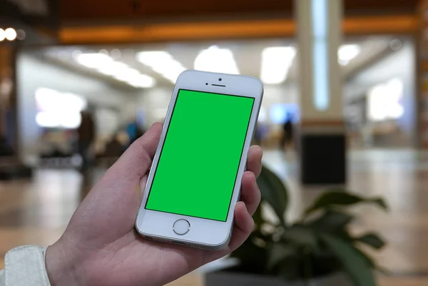 Mulher segura um dispositivo inteligente em branco com uma tela verde para o seu próprio conteúdo personalizado na frente da loja de maçãs — Fotografia de Stock