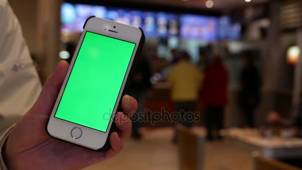 Mulher segurando iphone tela verde com pessoas desfocadas encomendar comida dentro do restaurante Mcdonalds — Vídeo de Stock