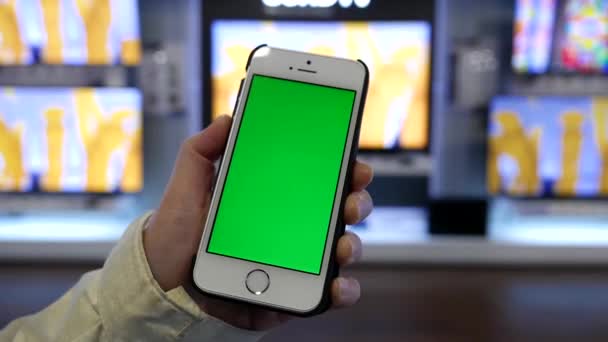 Motion de la femme tenant le téléphone à écran vert devant l'écran 4k Sony tv en vente à l'intérieur Best buy store — Video