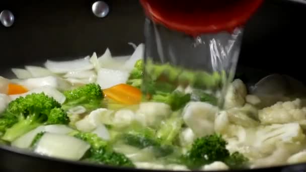 Close up of a woman cooking dumplings soup and pouring water in frying pan — Stock Video