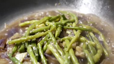 Bir kadın pişirme patlıcan ve sarımsak yeşil fasulye güveç tavada yakın çekim