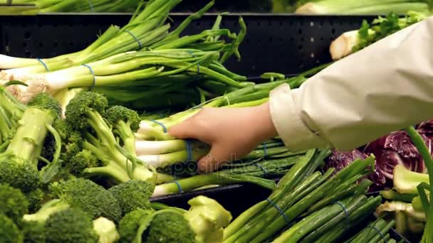 Movimiento lento de la mujer recogiendo cebolla verde dentro del supermercado — Vídeos de Stock