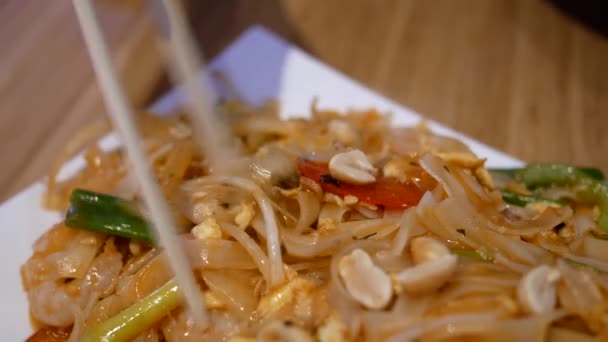 Pohyb ženy jíst thajské nudle pad uvnitř restaurace — Stock video