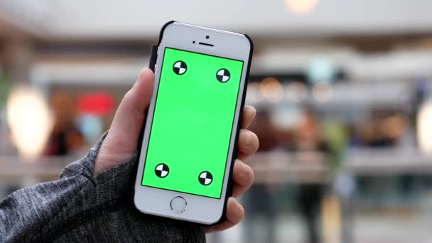 Movimiento de la mujer sosteniendo el teléfono de pantalla verde con personas borrosas cenando en la zona del patio de comidas — Vídeo de stock