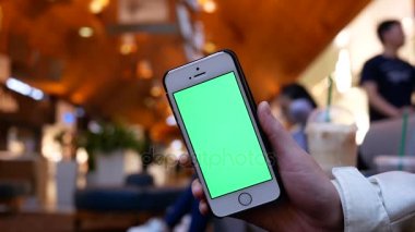 Yeşil perde telefon ile tutan kadın Hareket Bulanıklığı alışveriş ve alışveriş merkezi içinde oturan insanlar