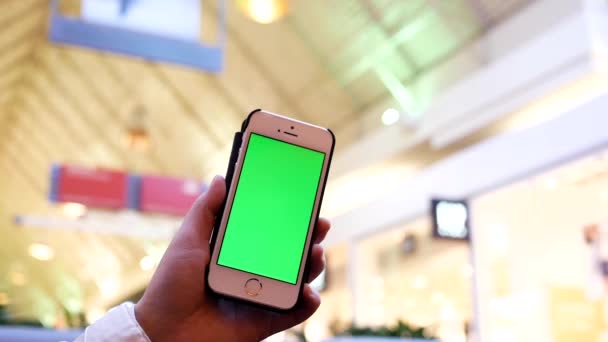 Movimento della donna che tiene il telefono verde dello schermo con la gente di sfocatura che compra e che riposa all'interno del centro commerciale — Video Stock