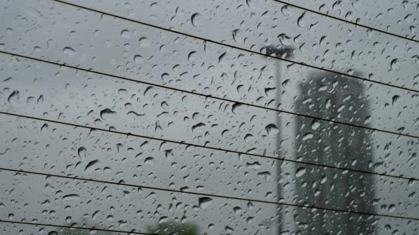 Κίνηση του βροχερή ημέρα προβολής και βροχή σταγόνες συρόμενη κάτω στο παρμπρίζ μέσα σε ένα αυτοκίνητο — Αρχείο Βίντεο