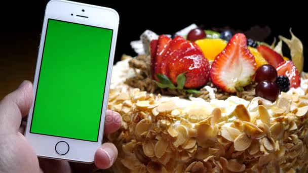 运动的水果生日蛋糕和黑色背景上的手绿屏电话 — 图库视频影像