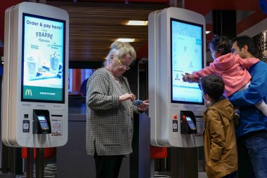 Makine ve cep telefonu Mcdonalds restoranda oynayan yaşlı kadın kendini aile sipariş gıda kontrol