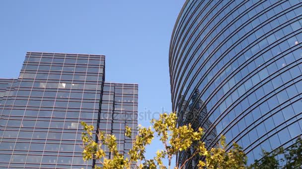 Movimento do céu azul com fachada de vidro refletida iluminada no edifício de escritórios moderno — Vídeo de Stock