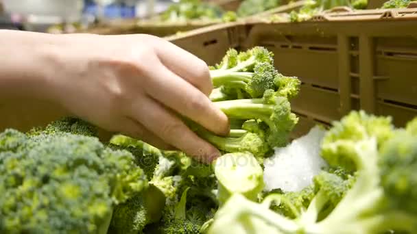 Beweging van de hand van de vrouw die broccoli plukt in de supermarkt — Stockvideo