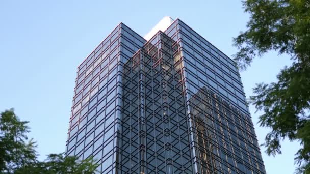 Movimento do céu azul com fachada de vidro refletida iluminada no edifício de escritórios moderno — Vídeo de Stock