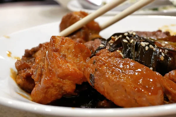 Mensen die eten van honing geglazuurde geroosterd varkensvlees hapjes op tafel binnen Chinees restaurant Stockfoto