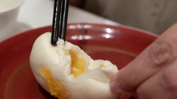 Movimiento de personas comiendo bollo de yema de huevo al vapor dentro del restaurante — Vídeo de stock