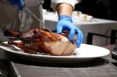 Şef müşteri için bir tabak içine kızarmış ördek kesme hareketi