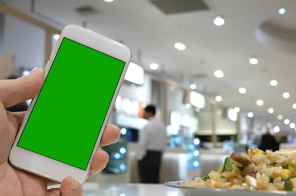 Chiuda in su telefono uomo della holding della schermo verde con sfocatura persone mangiare cibo all'interno del centro commerciale — Foto Stock