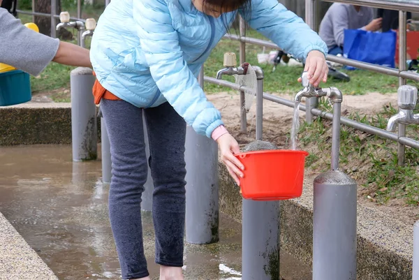 Motion of woman receiving water into a pot for washing hand at park