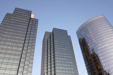 Modern ofis binasına yansıyan parlak cam cephe ile mavi gökyüzünün hareketi