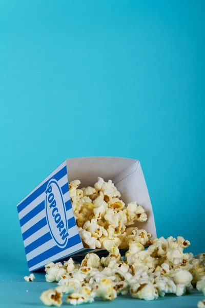 Popcorn hink mot en blå bakgrund — Stockfoto
