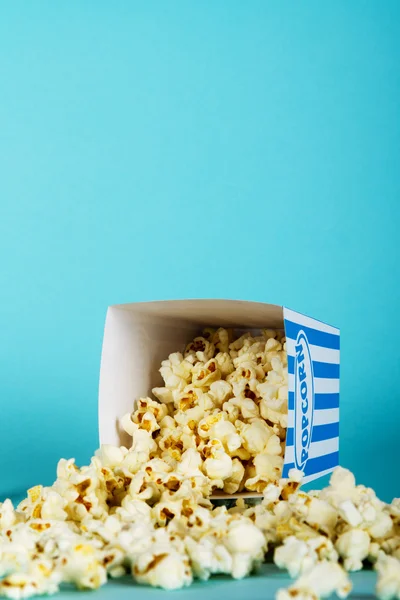 Plechovka popcorn na modrém pozadí — Stock fotografie