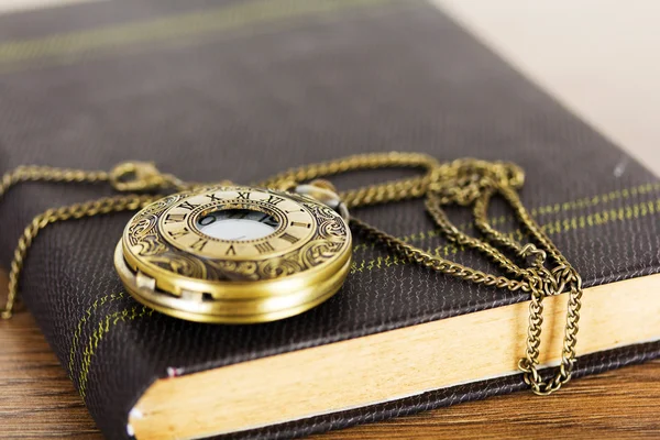 Zakhorloge en boek tegen een rustieke achtergrond — Stockfoto