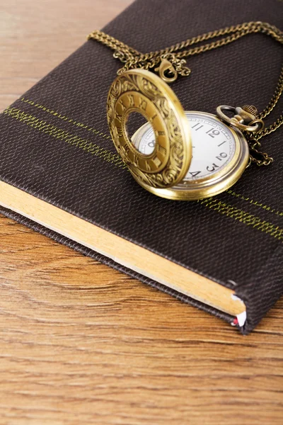 Pocket watch and book against a rustic background