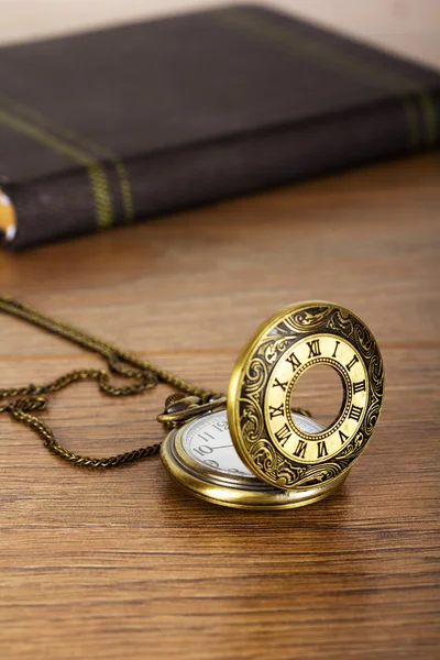 Reloj de bolsillo y libro sobre un fondo rústico — Foto de Stock