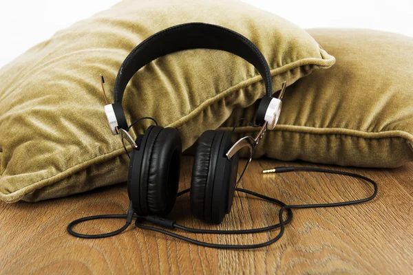 Kopfhörer auf Kissen auf einer Holzoberfläche — Stockfoto