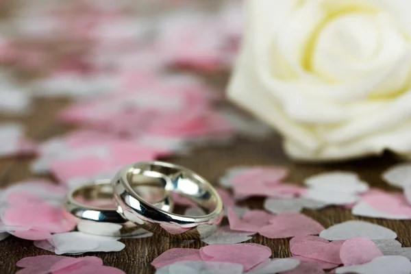 Anillos de boda sobre fondo de madera con confeti — Foto de Stock