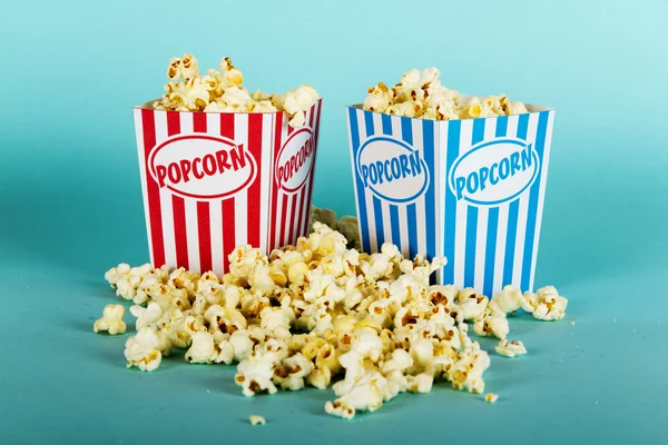 Plechovka popcorn na modrém pozadí — Stock fotografie