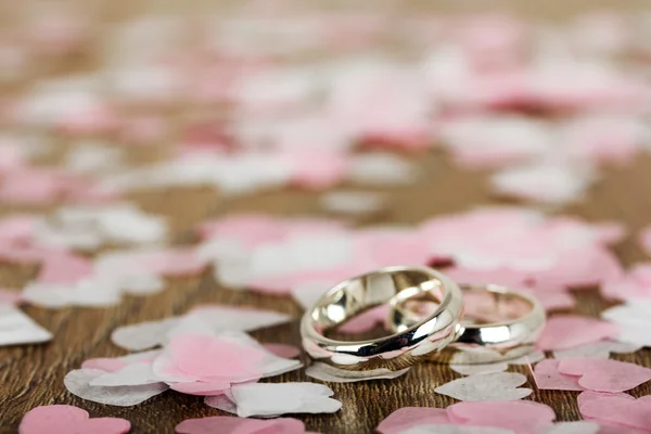 Anillos de boda sobre fondo de madera con confeti — Foto de Stock