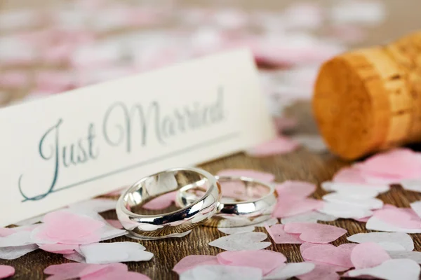 Anillos de boda sobre fondo de madera con confeti — Foto de Stock