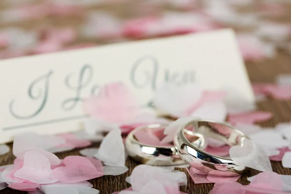 Anillos de boda sobre fondo de madera con confeti — Foto de Stock