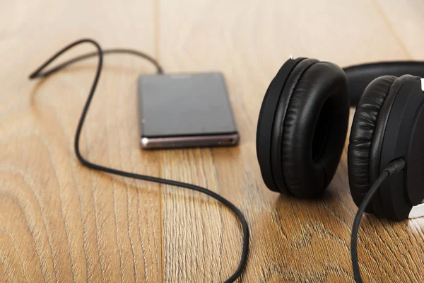 Auriculares y teléfono en una superficie de madera —  Fotos de Stock