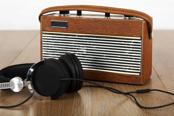 Headphones and old radio on wooden surface